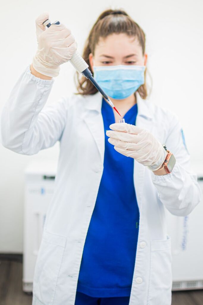 A female scientist in PPE handling a test tube with precision in a laboratory environment.
